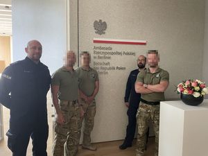 Trzej kontrterroryści i dwaj policjanci pozują do zdjęcia. W tle napis na ścianie: Ambasada RP w Berlinie.