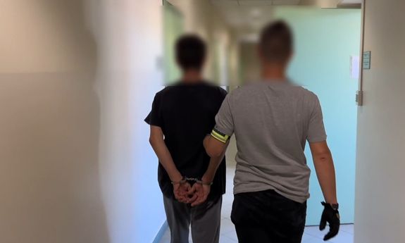 Policjant prowadzi zatrzymanego.