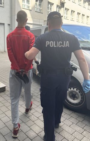 Policjanci prowadzą do radiowozu zatrzymanego.