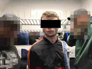 Zatrzymany mężczyzna z policjantami w wagonie kolejowym.
