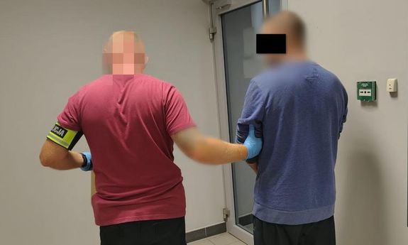 Policjant prowadzi zatrzymanego.