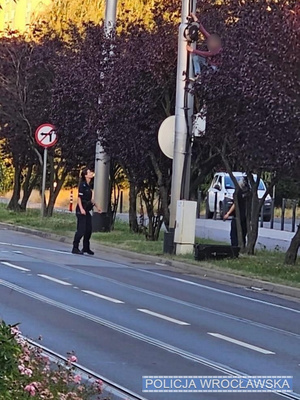 policjanci i strażacy stoją na podnośniku przy latarni.