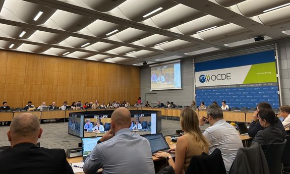 Uczestnicy spotkania zgromadzeni na sali w siedzibie głównej OECD w Paryżu.