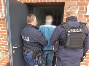 dwóch policjantów stoi z zatrzymanym.