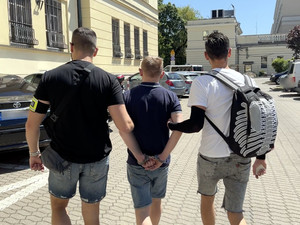 Dwaj policjanci prowadzą zatrzymanego.