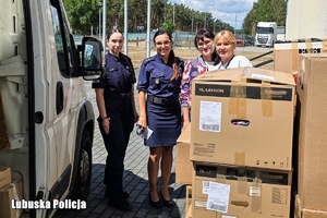 Dwie policjantki i dwie kobiety przy kartonach z darami. Z lewej strony widać fragment auta.