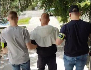 Dwaj policjanci prowadzą zatrzymanego.