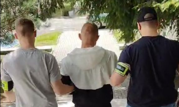 Dwaj policjanci prowadzą zatrzymanego.
