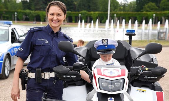 policjantka stoi obok motocykla, na nim siedzi dziecko.