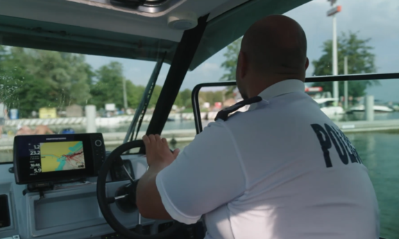 Plecy policjanta, który pływa łodzią po jeziorze.
