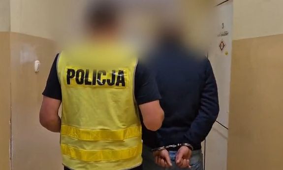 policjant idzie z zatrzymanym przez korytarz.