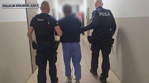 dwóch policjantów idzie z zatrzymanym.