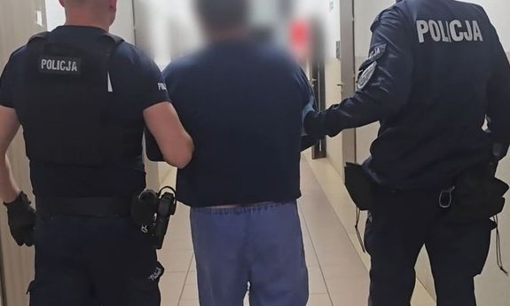 dwóch policjantów idzie z zatrzymanym.