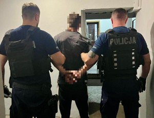 dwóch policjantów idzie z zatrzymanym.