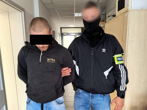 Policjant prowadzi zatrzymanego.