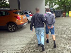 Policjant prowadzi zatrzymanego.