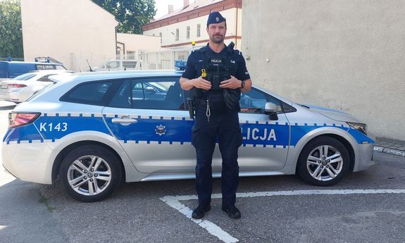 Policjant stoi przy radiowozie.