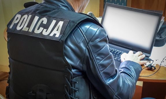Policjant pisze na komputerze.