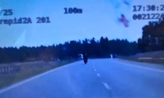 Stopklatka z nagrania wideorejestratora przedstawia mężczyzn jadącego na motocyklu.