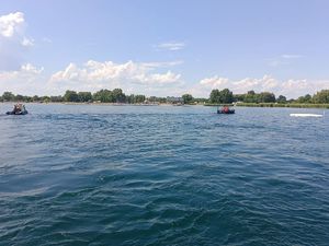 Łodzie ratunkowe na zbiorniku wodnym i wywrócona do góry dnem żaglówka.