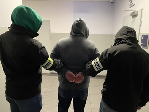 Dwaj policjanci prowadzą zatrzymanego.