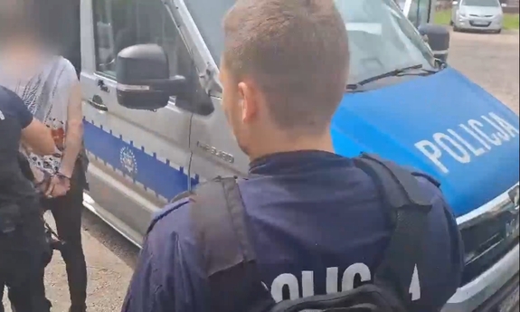 Policjant stoi przy radiowozie.