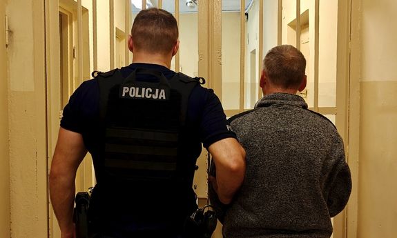 Policjant prowadzi zatrzymanego.