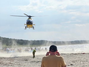 Śmigłowiec na plażą. W głębi duża grupa osób.