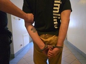 Policjant prowadzi zatrzymanego.