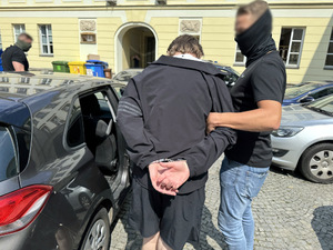 policjanci idą z zatrzymanym.