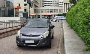 Na zdjęciu pojazd marki Hyundai , w oddali policyjny radiowóz