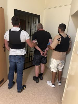 Dwaj policjanci prowadzą zatrzymanego.