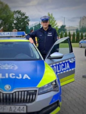 Policjant ruchu drogowego stoi w otwartych drzwiach radiowozu.
