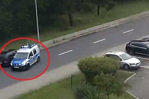 Stopklatka z monitoringu. Radiowóz obok zatrzymanego samochodu.