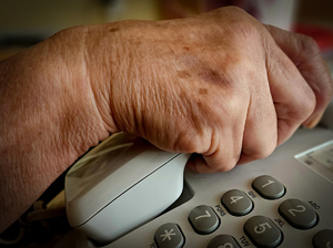 Dłoń na słuchawce telefonu stacjonarnego.