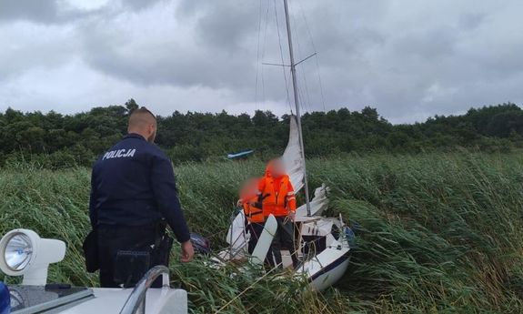 Policjant na policyjnej łodzi, i żaglówka, która utknęła w trzcinach.