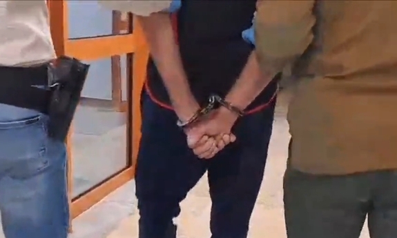 Zatrzymany w kajdankach prowadzony przez policjantów.