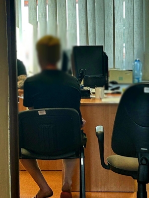 Zatrzymany mężczyzna siedzi na krześle podczas przesłuchania.