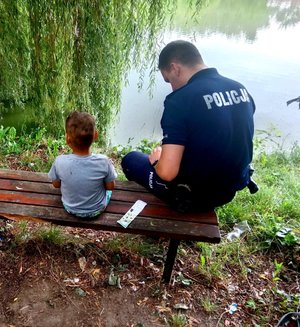 Policjant siedzący na ławce z dzieckiem.