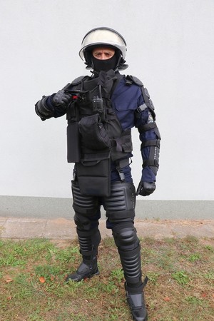 Zdjęcie przedstawia funkcjonariusza Policji w zestawie przeciwuderzeniowym z kamizelką OPP-4K