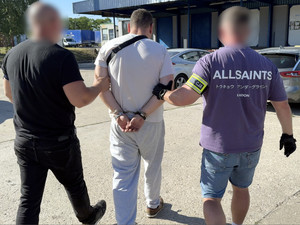 Dwaj policjanci prowadzą zatrzymanego.