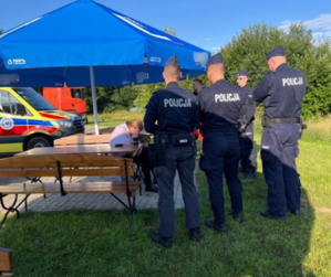 Czterej policjanci stoją obok mężczyzny siedzącego na ławce.