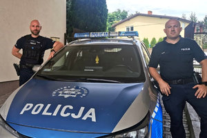 Dwaj policjanci przy radiowozie.