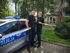 Na zdjęciu widać dwoje policjantów przy radiowozie.