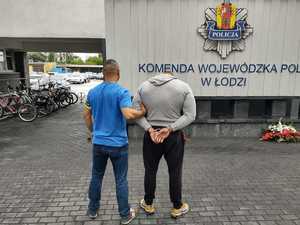 Policjant stoi z zatrzymanym mężczyzną.