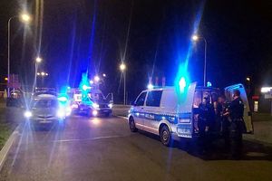 Radiowozy policyjne i policjanci na drodze.