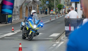 Policjant na motocyklu służbowym w trakcie przejazdu z zawodnikami.