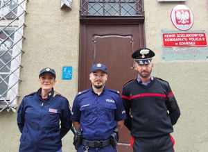 Dwoje polskich policjantów wraz z włoskim policjantem przed budynkiem rewiru dzielnicowych w Gdańsku.