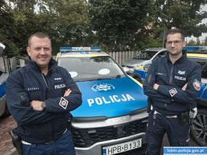 policjanci stoją przy radiowozie.