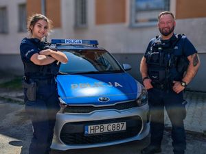 Dwoje policjantów przy radiowozie.
